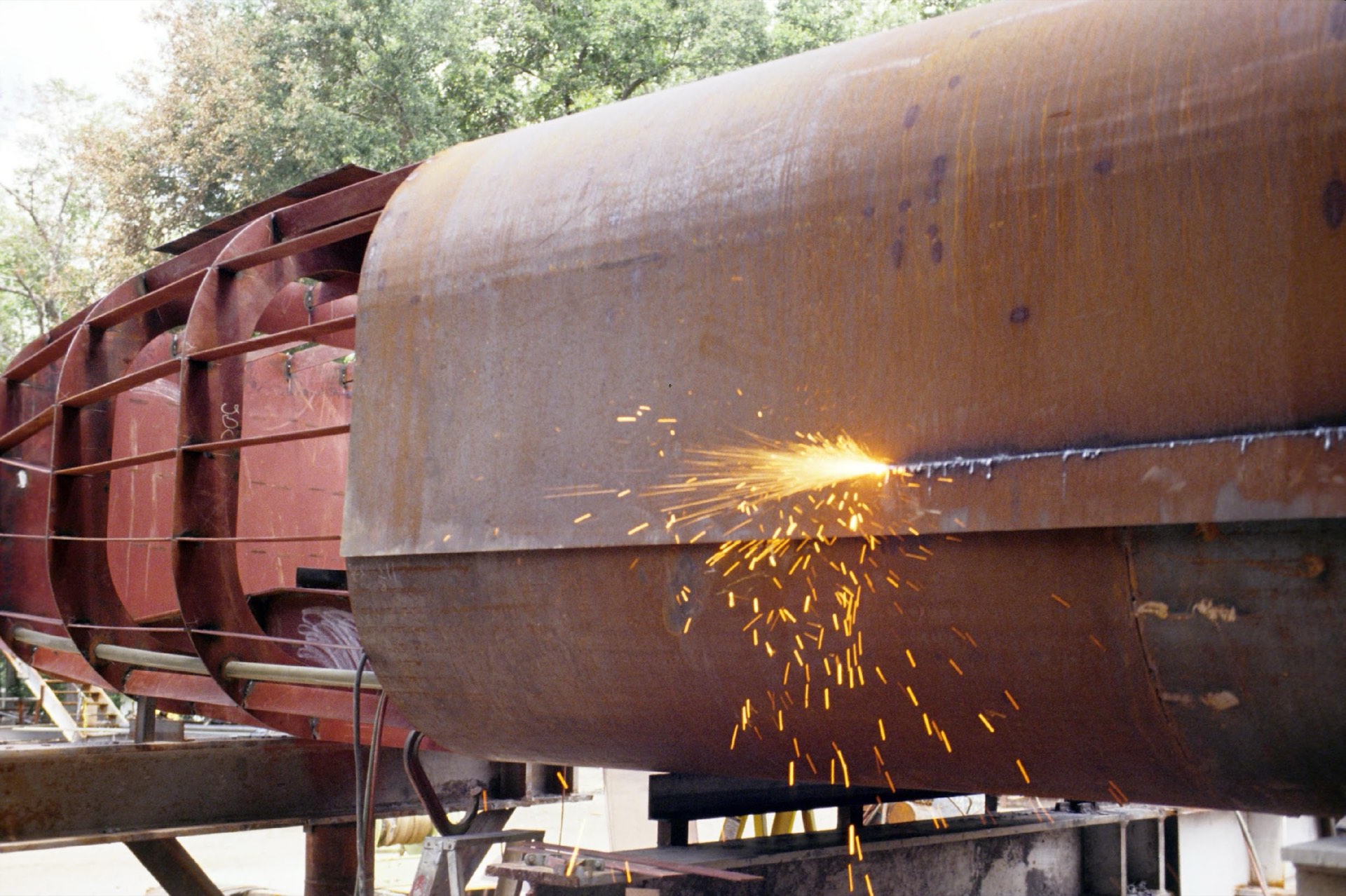 Welder cutting steel with a shower of sparks in the fabrication area at Gulf County Shipbuilding